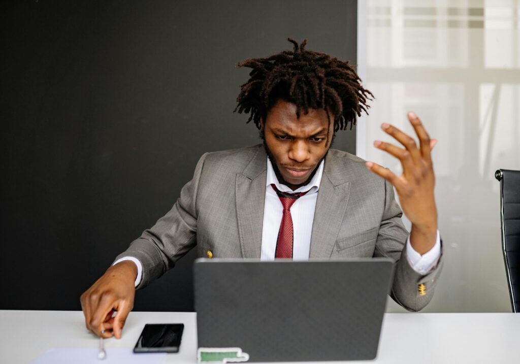 Businessman in a suit frustrated while working on a laptop at his desk.